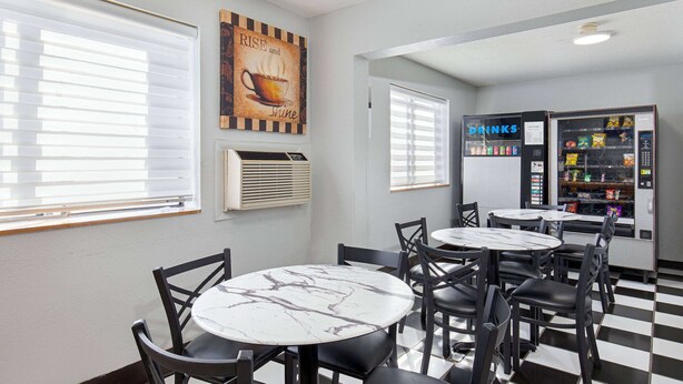 A cafe with round tables and chairs, a vending machine, and a wall with a motivational quote.
