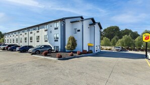 A modern hotel with a parking lot, multiple cars, and a sign for a nearby restaurant. - Super 8 by Wyndham Johnson City (Johnson City)