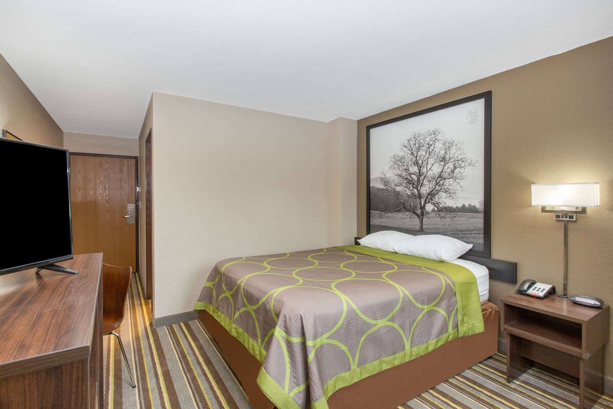 Una habitación de hotel con cama, televisión, escritorio y lámpara.