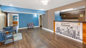 Un área de recepción con mostrador de madera, pared azul y un cartel con vista a la ciudad.