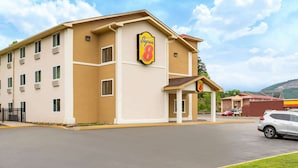 Un hotel Super 8 con fachada color beige, varias ventanas y un estacionamiento con algunos automóviles.