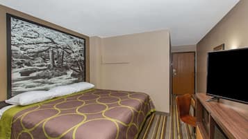 A hotel room with a bed, a television, a desk, and a large framed picture on the wall.