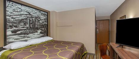Habitación de hotel con cama, televisor, escritorio y un cuadro grande enmarcado en la pared.
