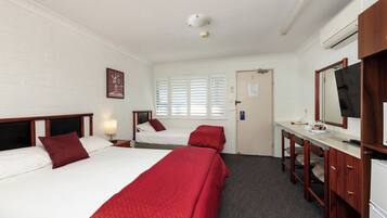 A hotel room with two beds, a desk with a mirror, and a television.