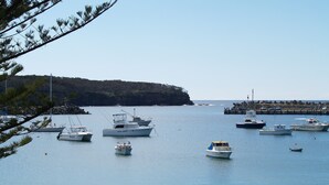 Un puerto deportivo con varias embarcaciones amarradas, un área verde con bancos y una vista despejada del agua.