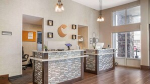 A reception area with two counters, a large wall clock, and a view of the outside through large windows.