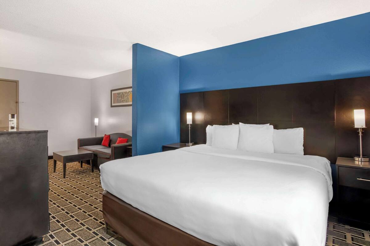A hotel room with a large bed, a desk, a chair, and a nightstand.