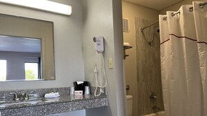 A bathroom with a granite countertop, a hairdryer mounted on the wall, a shower curtain, and a toilet. - Red Roof Inn Kimball, TN - I-24 (Jasper)