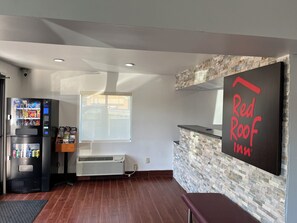 A Red Roof Inn reception area with a vending machine, a large window, and a stone-textured wall. - Red Roof Inn Kimball, TN - I-24 (Jasper)