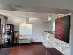 A Red Roof Inn reception area with a vending machine, a large window, and a stone-textured wall. - Red Roof Inn Kimball, TN - I-24 (Jasper)