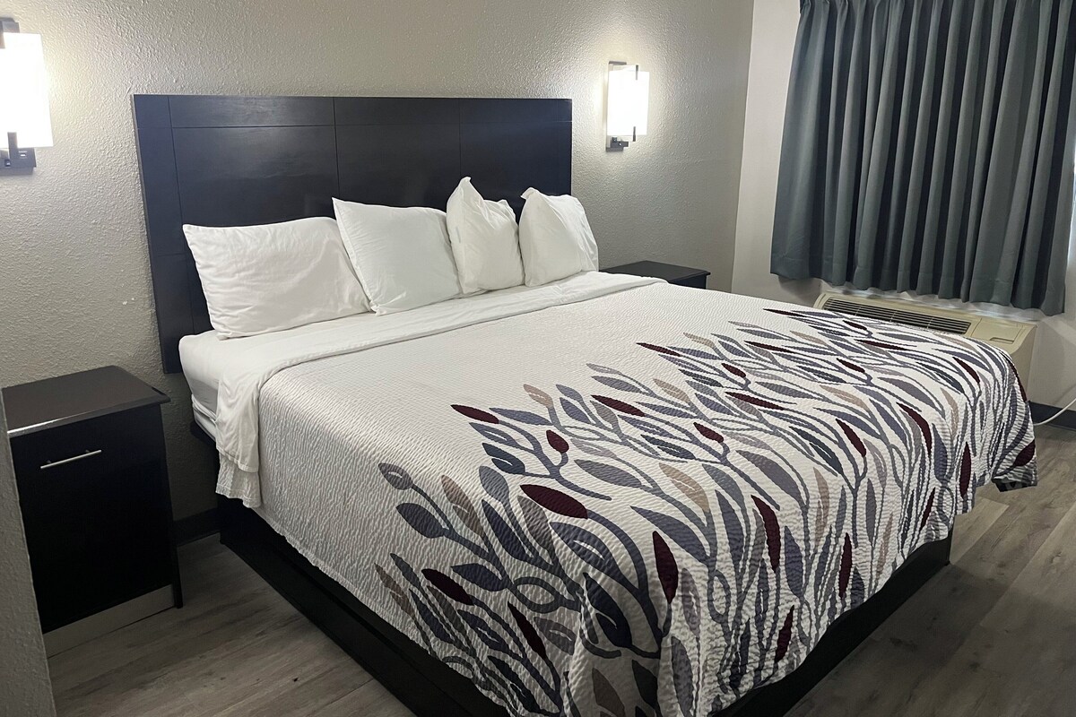 A neatly made bed with a patterned bedspread, a dark headboard, and two bedside tables.