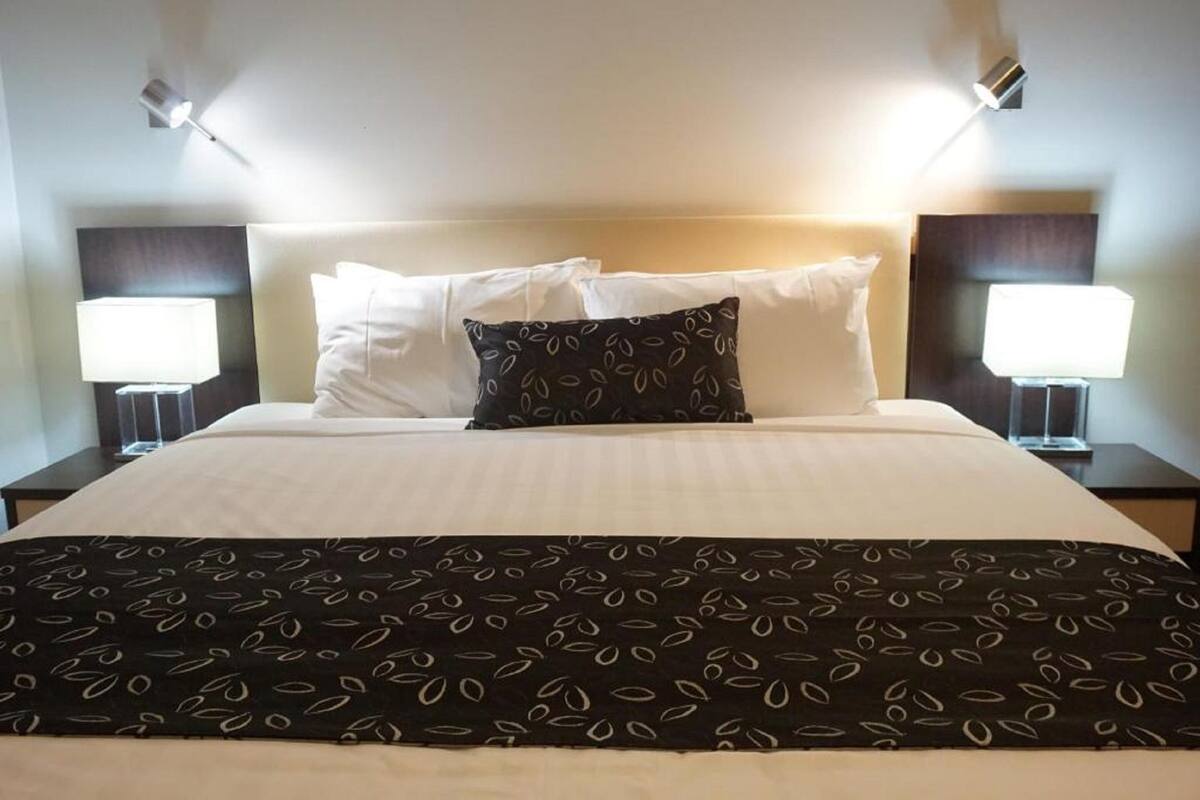 A neatly made bed with a patterned throw, two bedside lamps, and a headboard.
