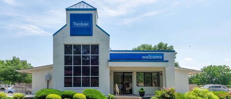 A Travelodge hotel with a welcoming entrance, a large window, and a blue sign.