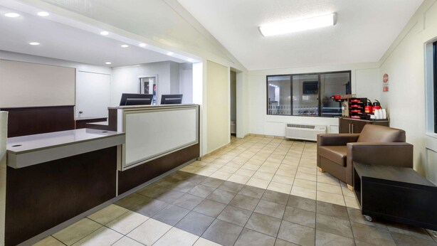 Un área de recepción con mostrador, una zona de estar con sofá y sillón, y un ventanal con vistas al exterior.