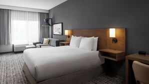 A modern hotel room with a large bed, bedside tables, a desk, and a chair.