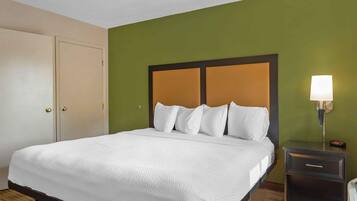 Una habitación de hotel con una cama, una mesita de noche con lámpara y un armario.