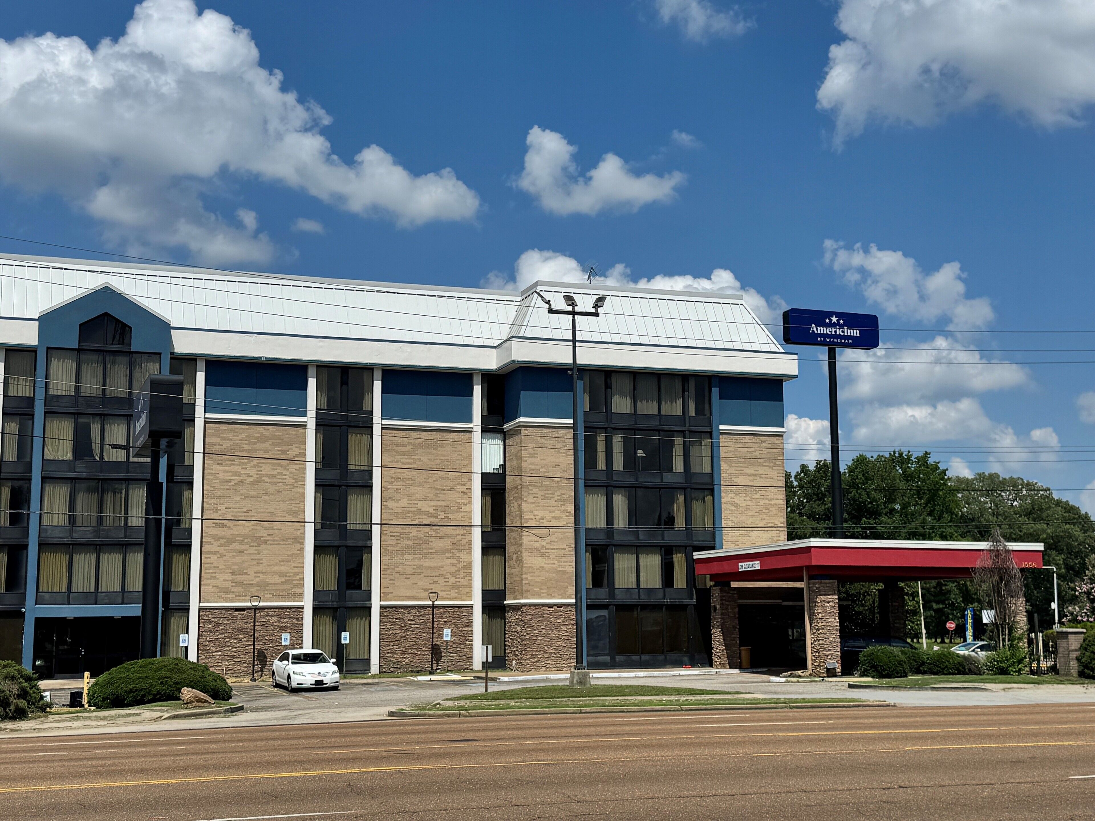 A hotel with a modern design, featuring a prominent entrance with a red awning and a sign indicating the name 'AmericInn'.
