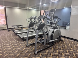 Un gimnasio con cintas de correr, elípticas y mancuernas.