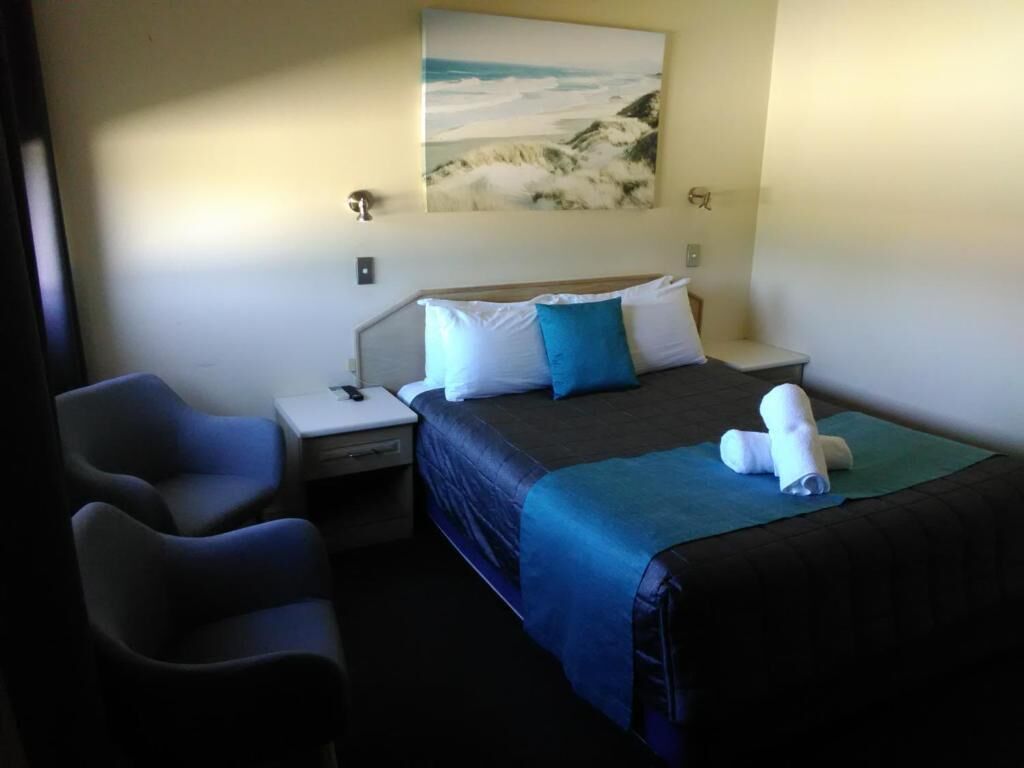 A hotel room with a bed, bedside tables, a desk, and a chair.