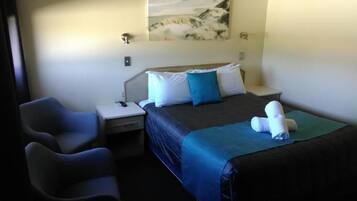 A hotel room with a bed, bedside tables, a desk, and a chair.