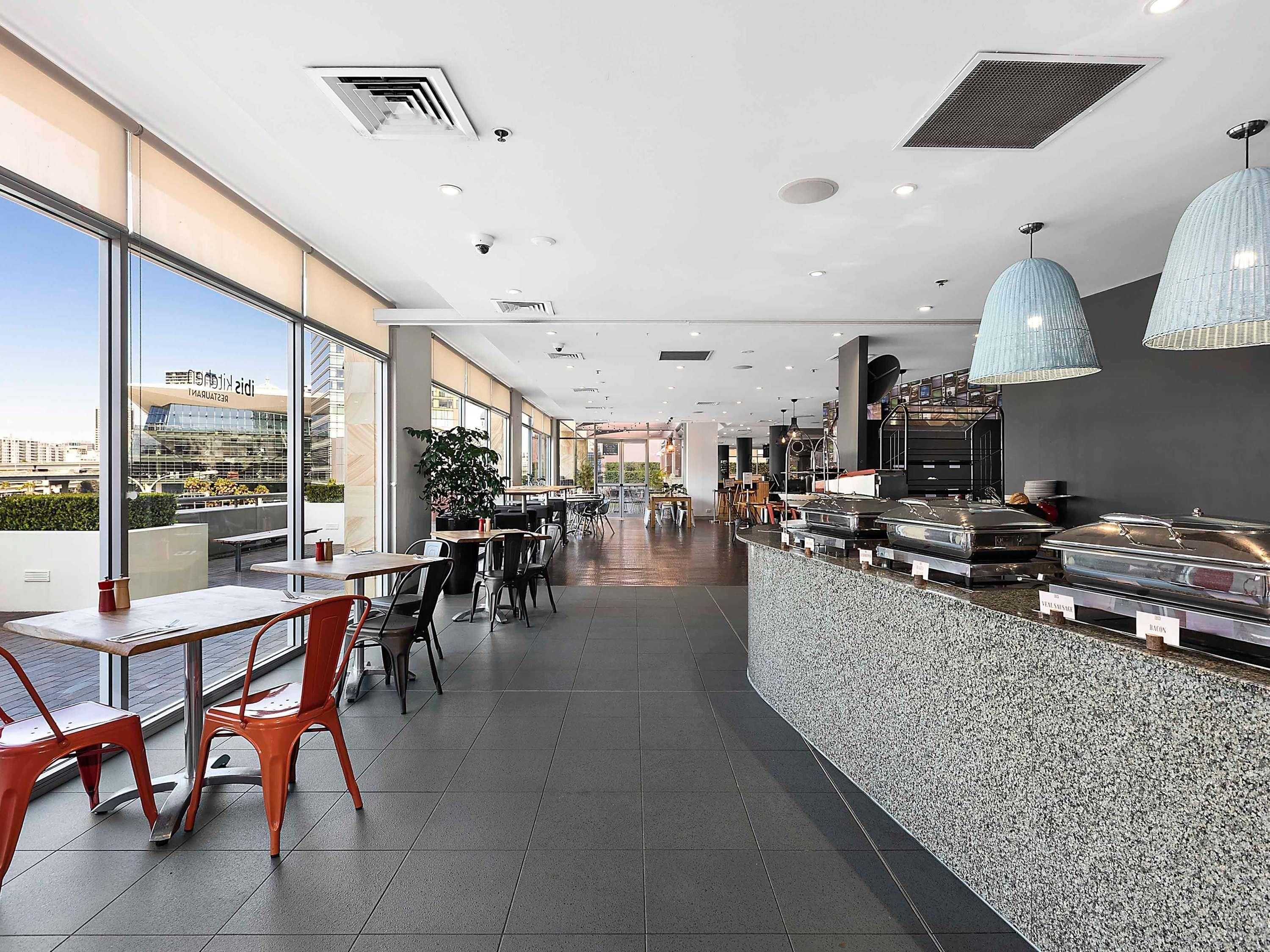 Un restaurant moderne doté d’un long comptoir, d’un espace salon et de grandes fenêtres offrant une vue sur la ville.