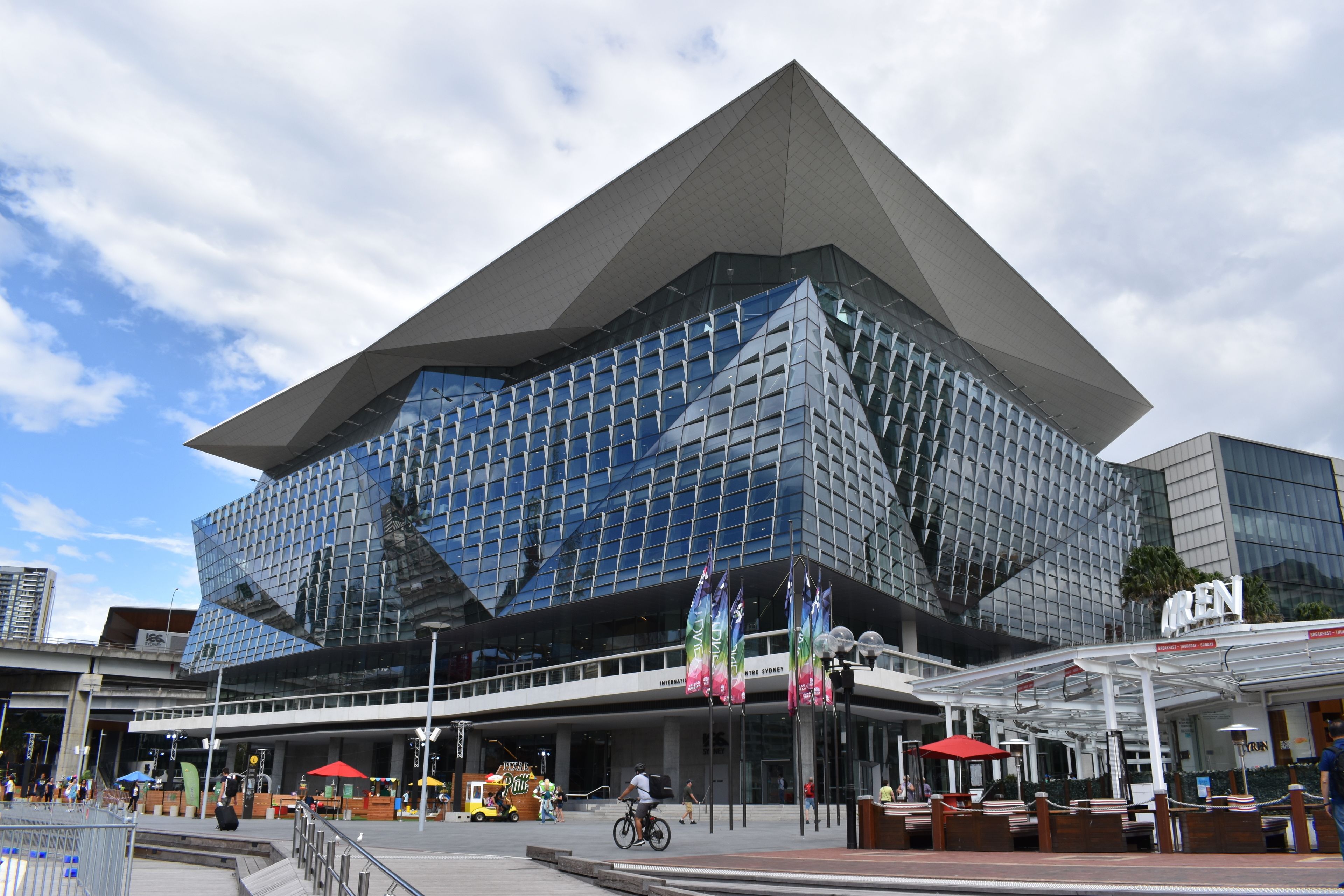 A modern building with a distinctive geometric design, featuring a large glass facade and a prominent overhang.