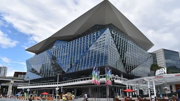 A modern building with a distinctive geometric design, featuring a large glass facade and a prominent overhang.