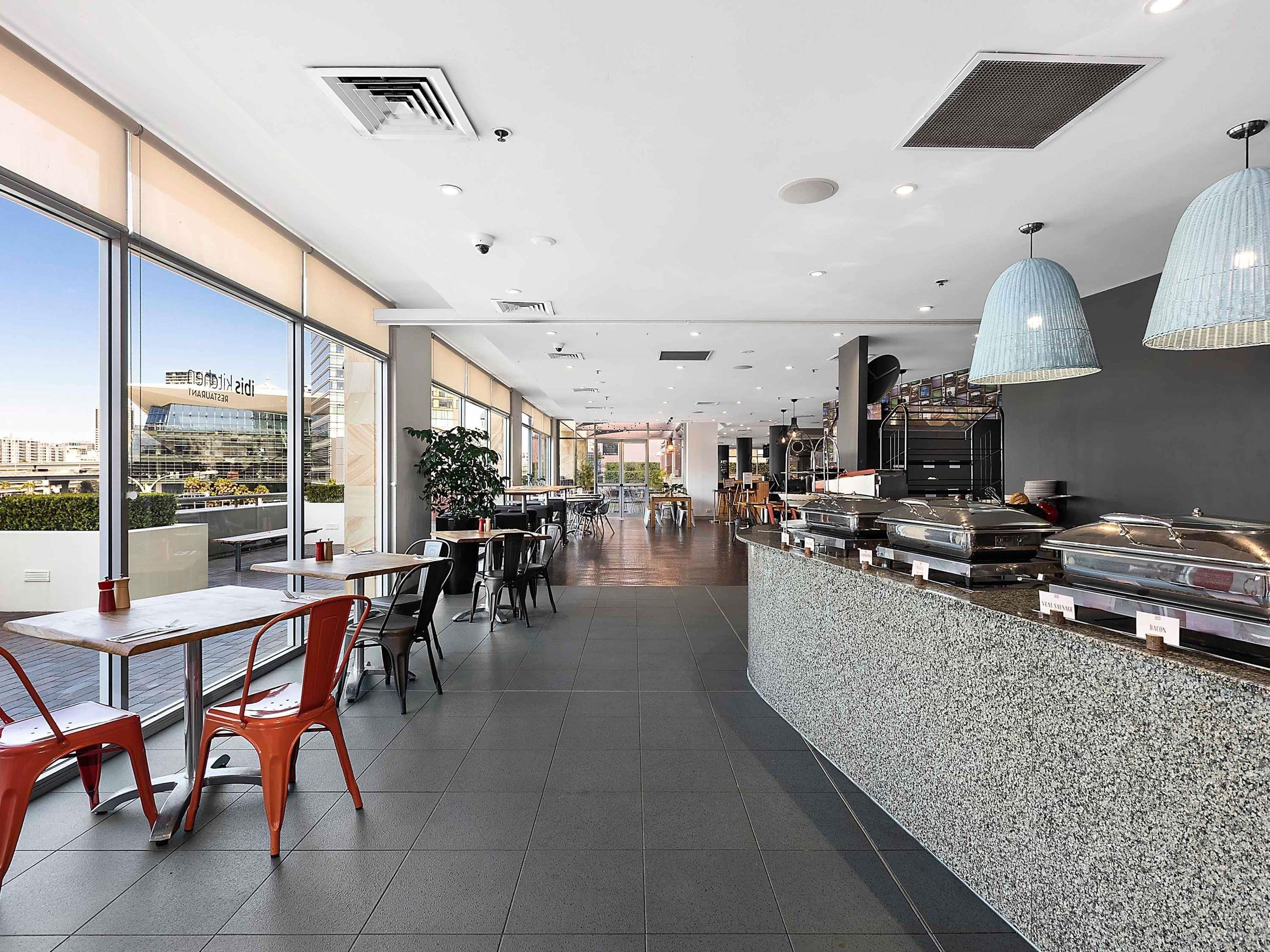 A modern restaurant with a long counter, seating area, and large windows.
