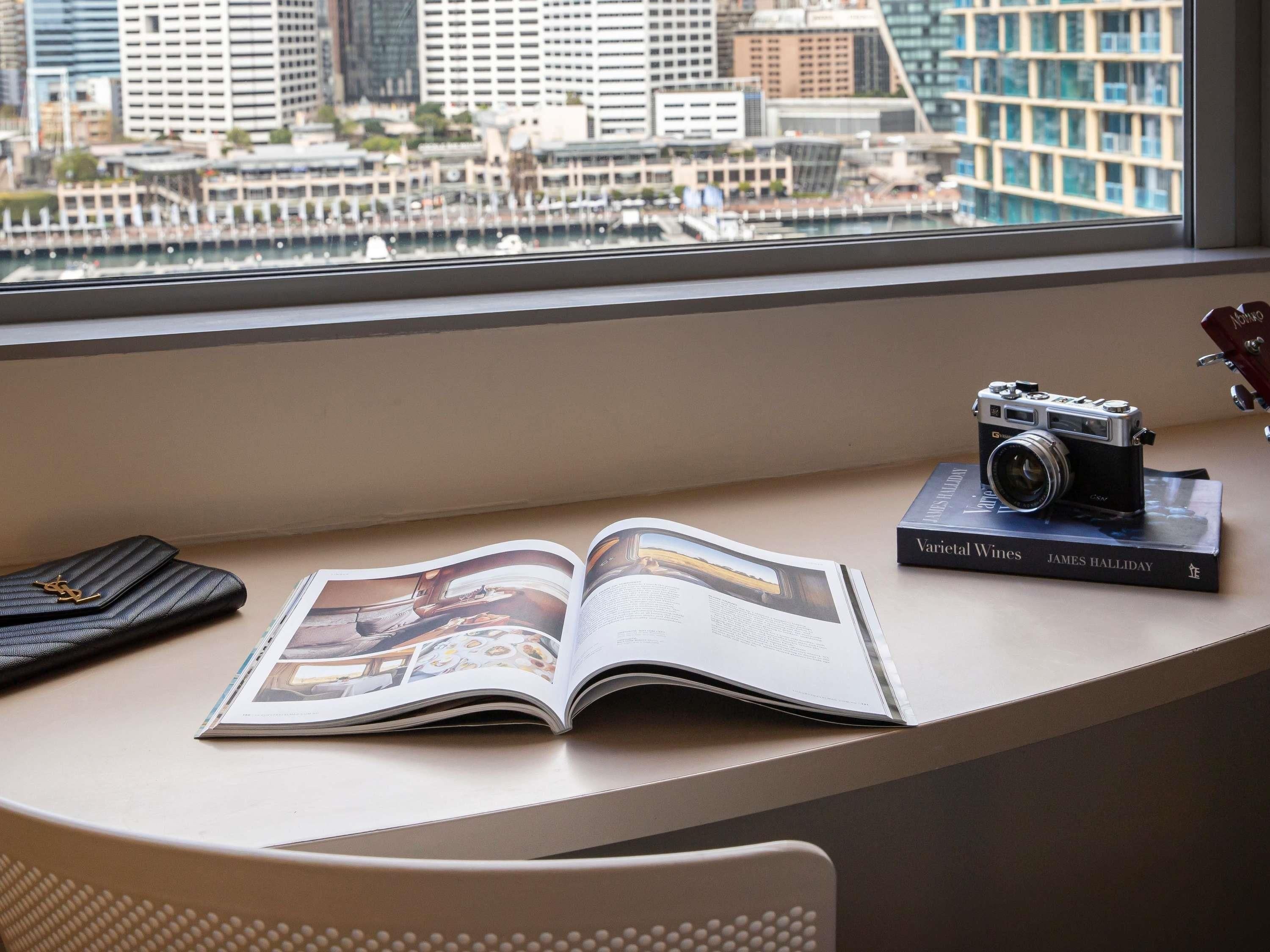 A window seat with a book, a camera, and a handbag.