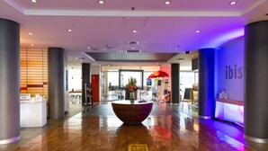 A spacious lobby with a wooden reception desk, a large planter with flowers, and a sign for 'ibis'. - ibis Sydney Darling Harbour (Sydney)