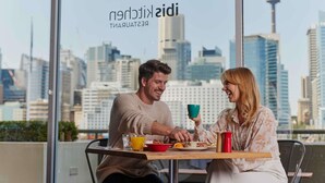 A couple dining at a table with a city skyline view, featuring a restaurant sign with the name 'Sidi'. - ibis Sydney Darling Harbour (Sydney)