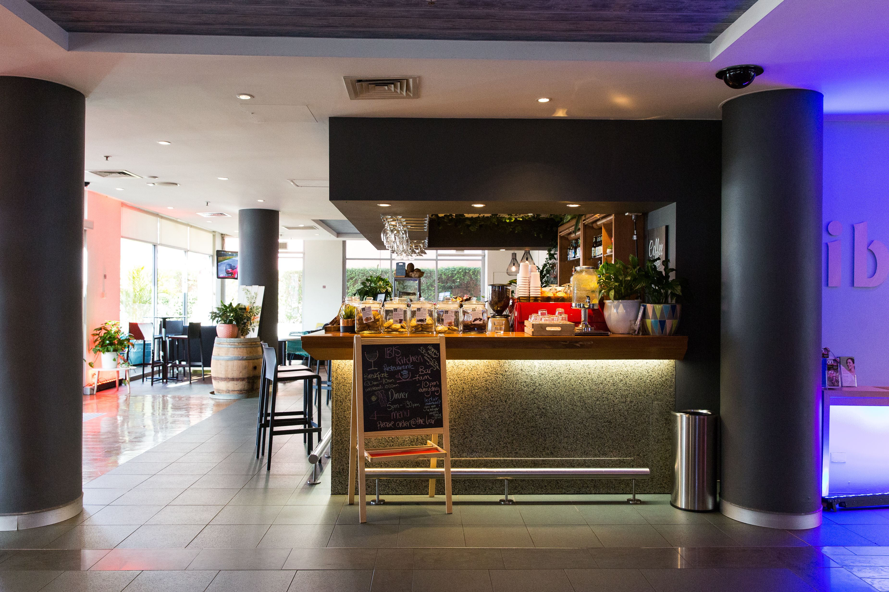 A modern bar area with a chalkboard menu, seating, and a view of the outdoors.
