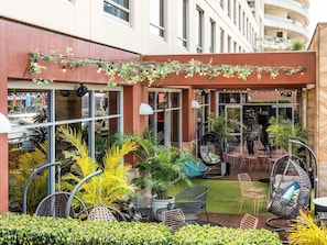 A restaurant with outdoor seating, including chairs and tables, surrounded by greenery and a hanging light fixture. - ibis Sydney Darling Harbour (Sydney)