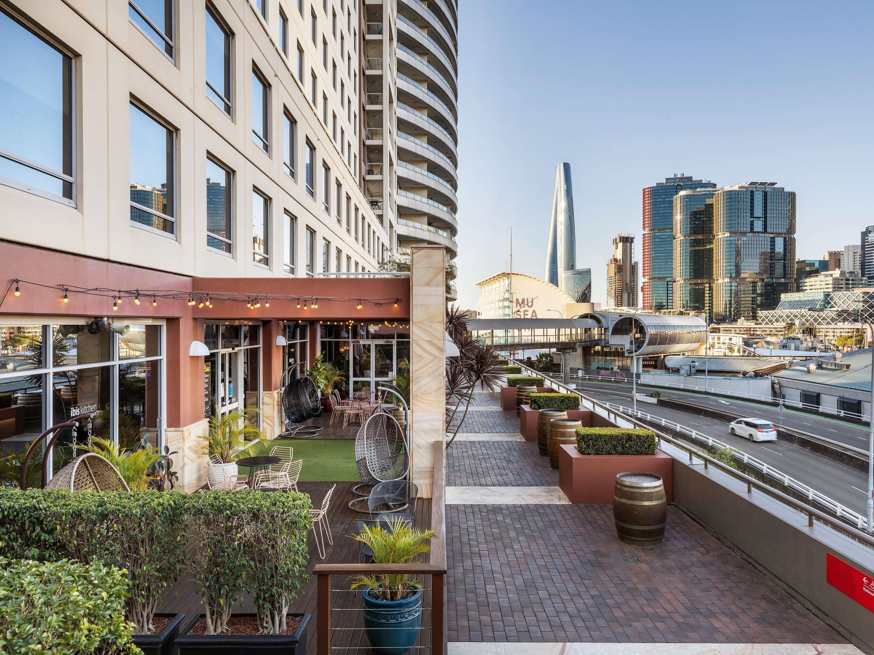 A rooftop terrace with outdoor seating, potted plants, and a view of the city skyline.