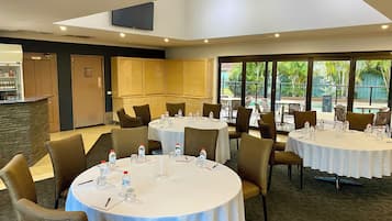 A conference room with round tables and chairs, equipped with water bottles and notepads.