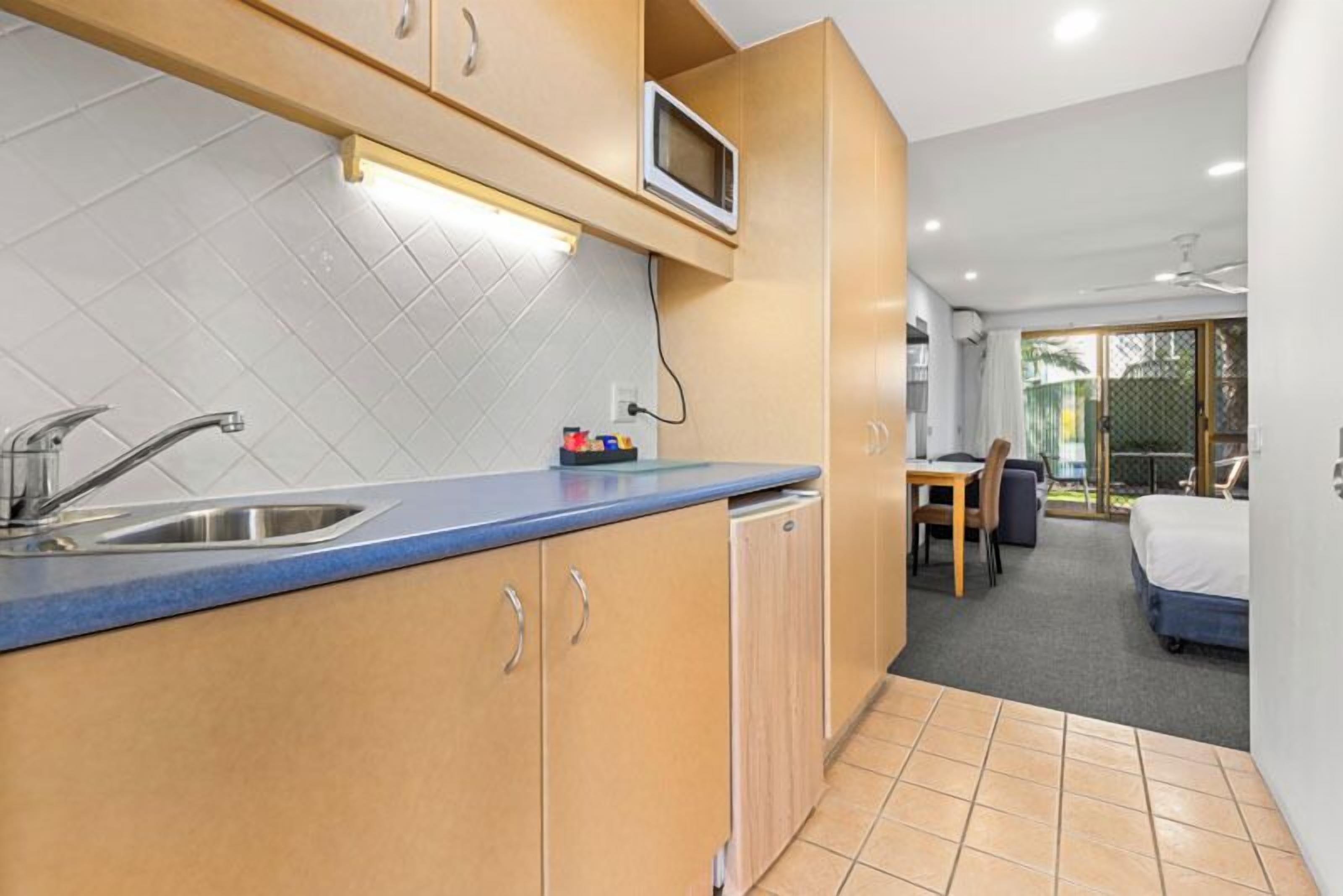 Cocina compacta con microondas, lavabo y una pequeña zona de comedor.
