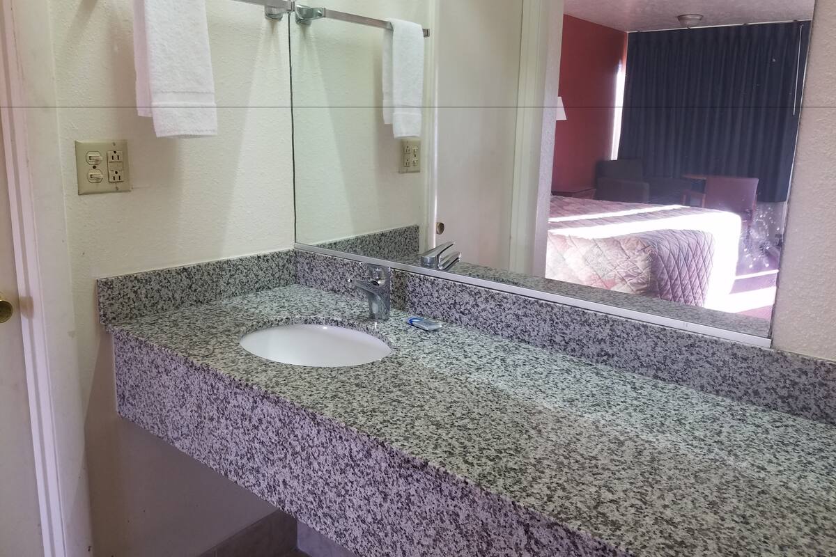 Une salle de bain avec un comptoir en granit, un lavabo et un miroir.