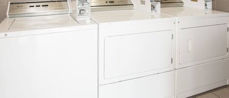 A row of white stacked washer and dryer units in a laundry room.
