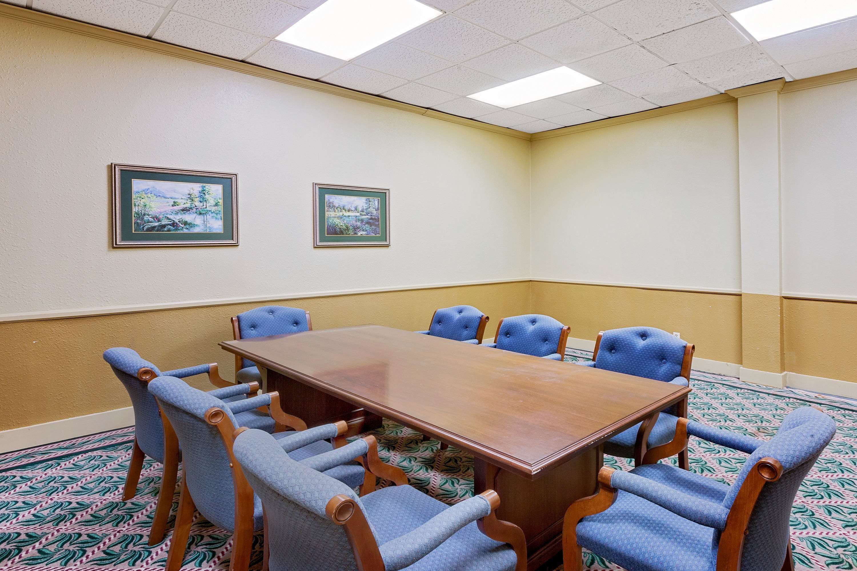 A conference room with a wooden table and eight blue upholstered chairs.