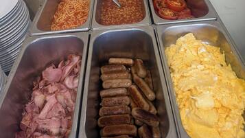A buffet with various food options including sausages, eggs, beans, and tomatoes.