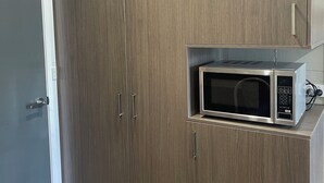 A kitchen with a built-in microwave and wooden cabinets. - Cootamundra Gardens Motel (Cootamundra)
