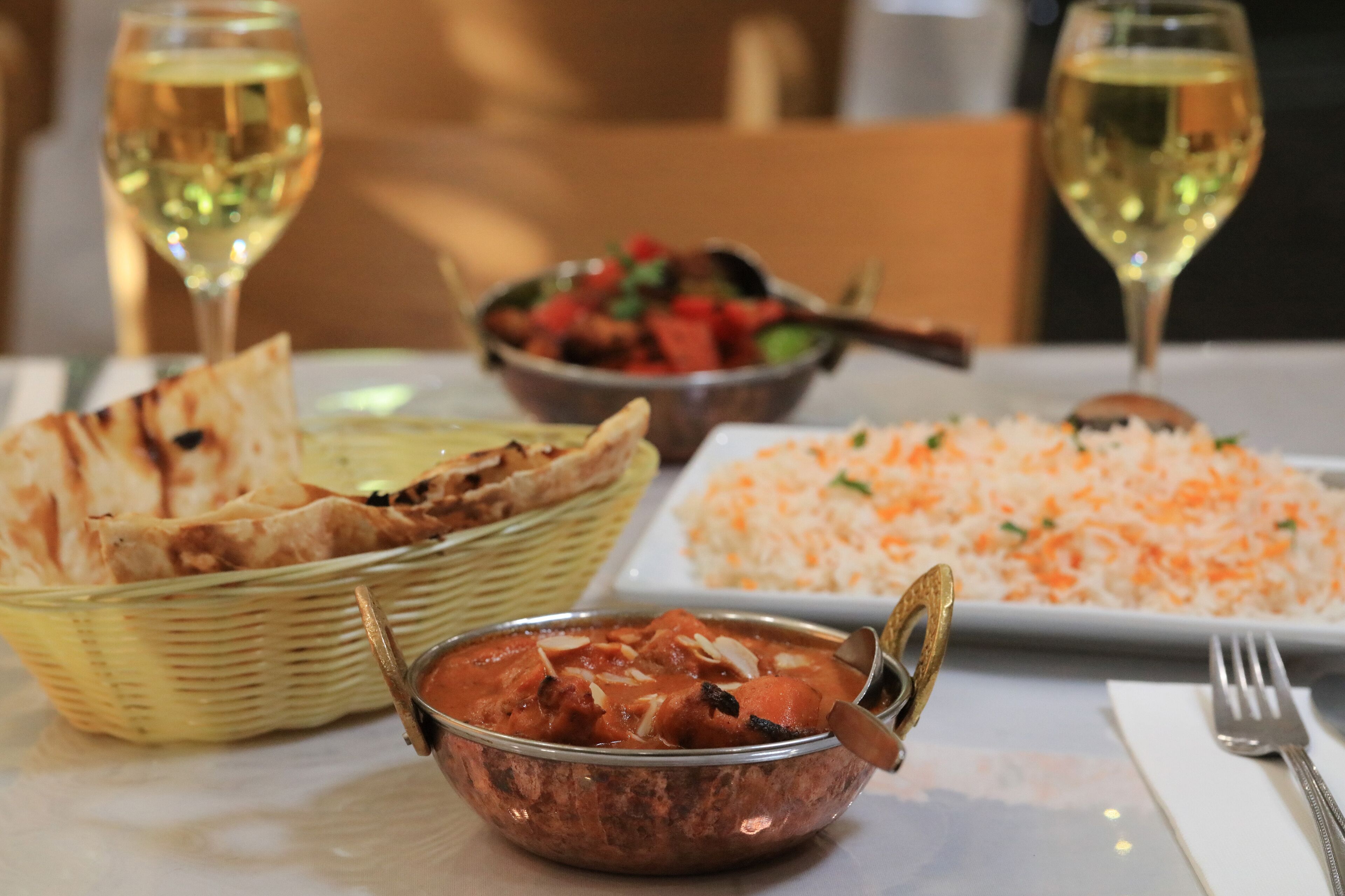 Una mesa con diversos platos, incluyendo pan naan, un cuenco de curry y una fuente de arroz.