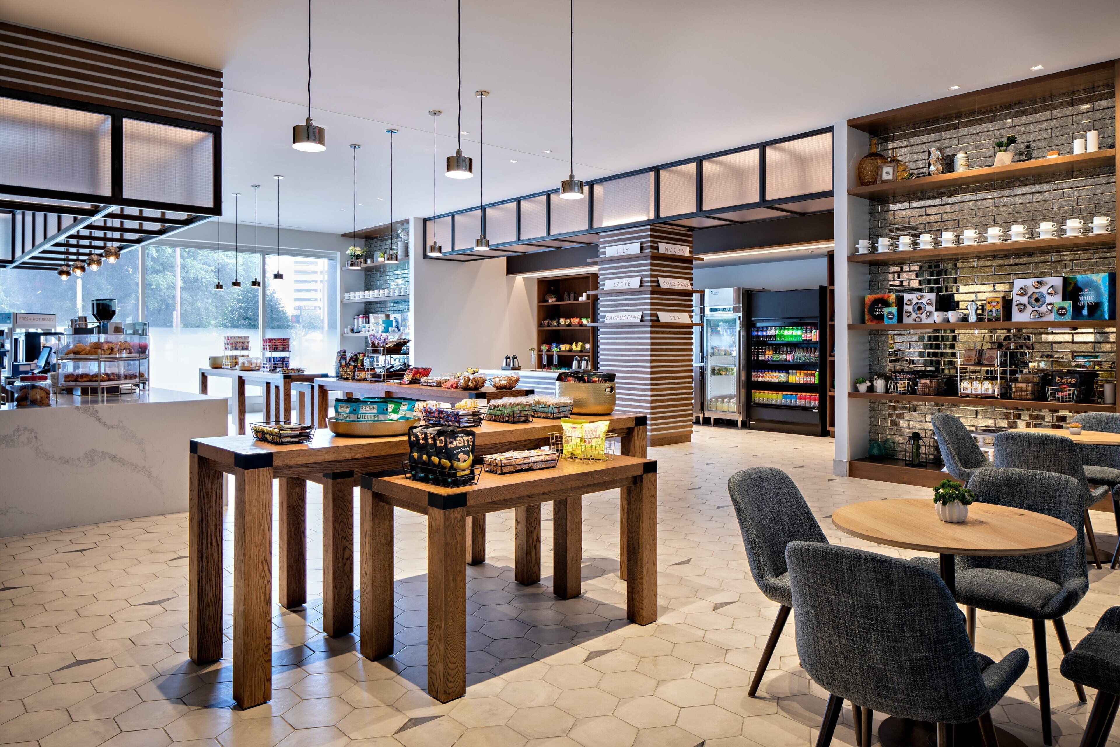 A modern café with wooden tables and chairs, a brick wall display, and a large window providing natural light.