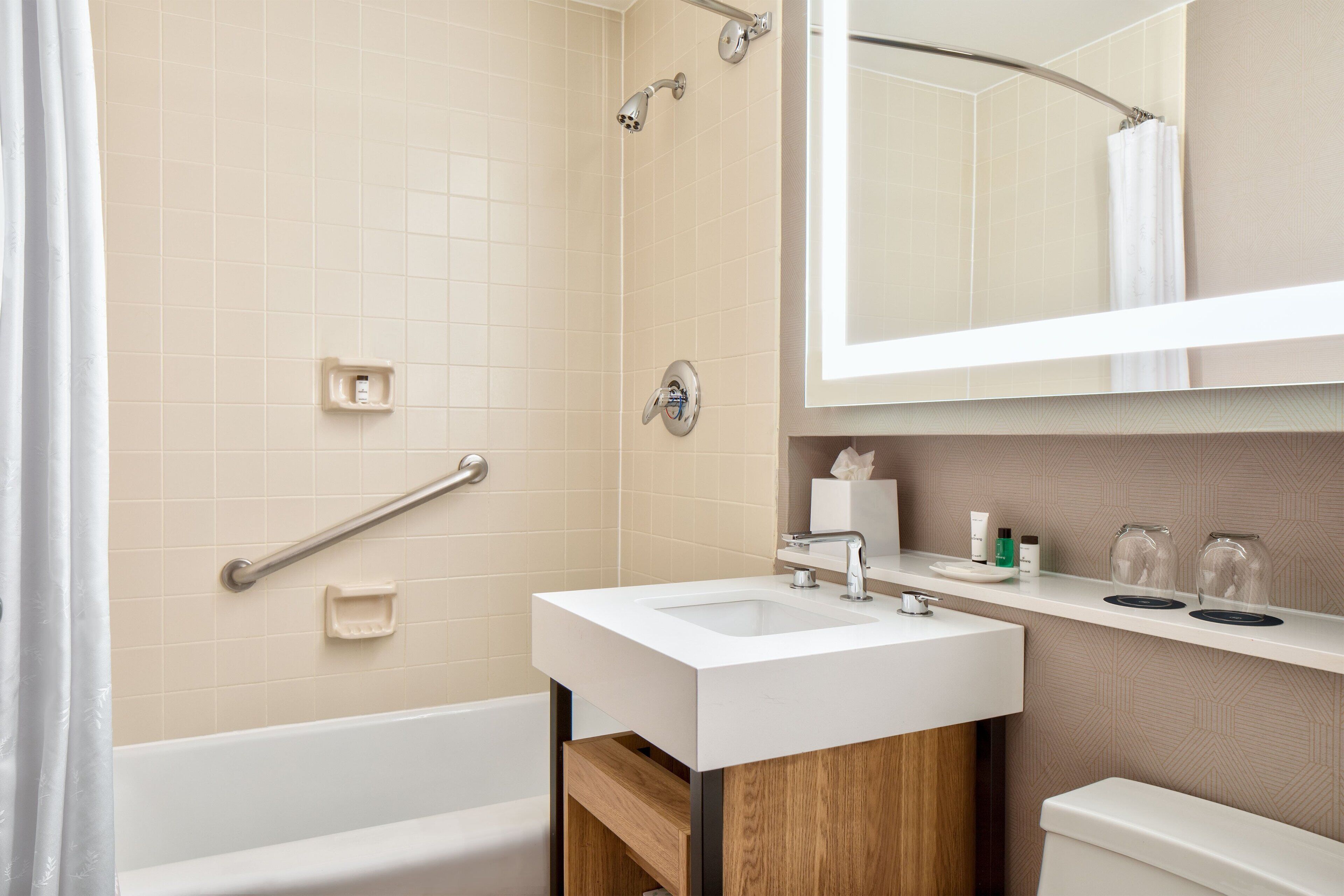 A modern bathroom with a bathtub, a sink, a mirror, and a shower.