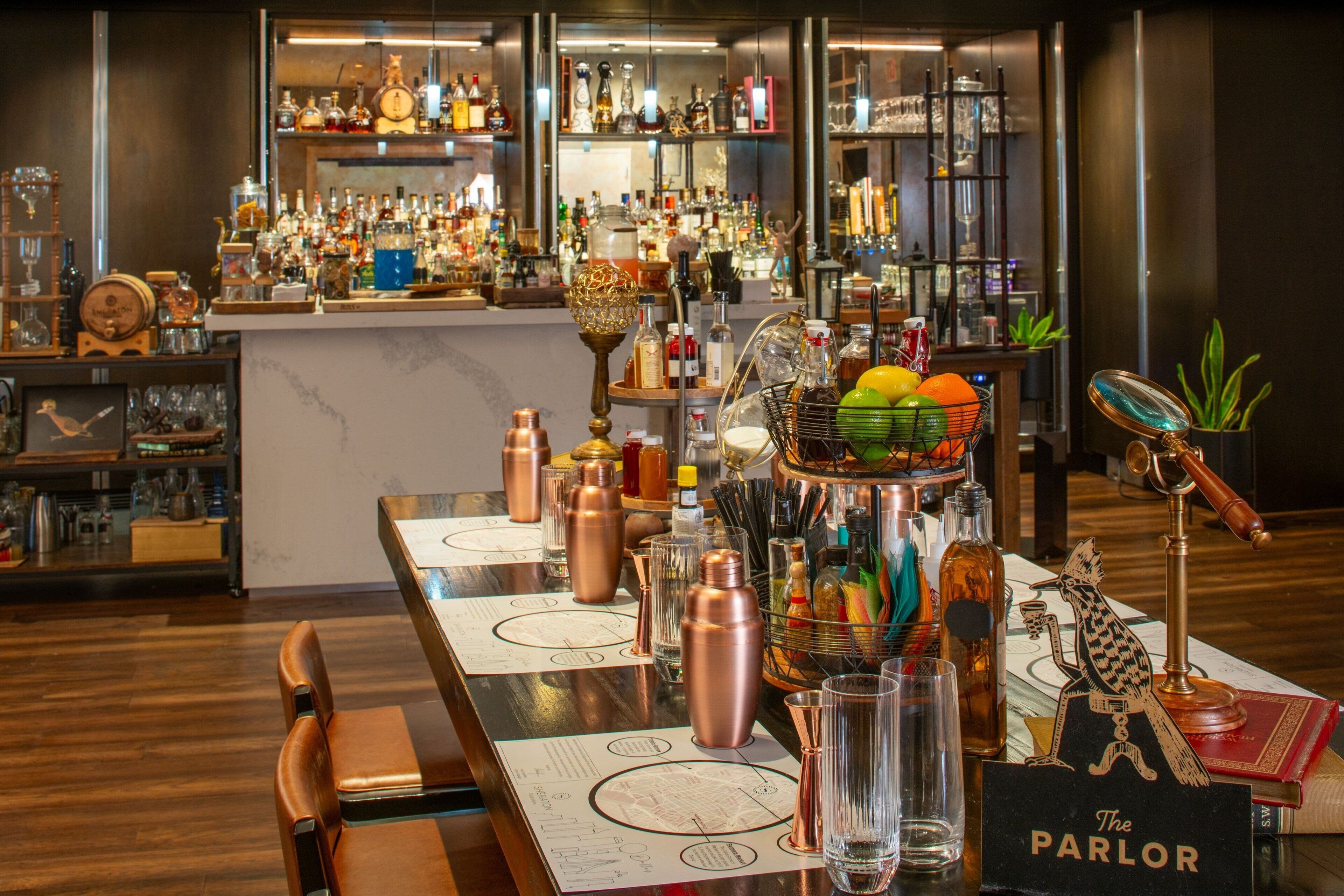 A bar area with a wooden bar counter, copper bar tools, and a variety of bottles and glasses.