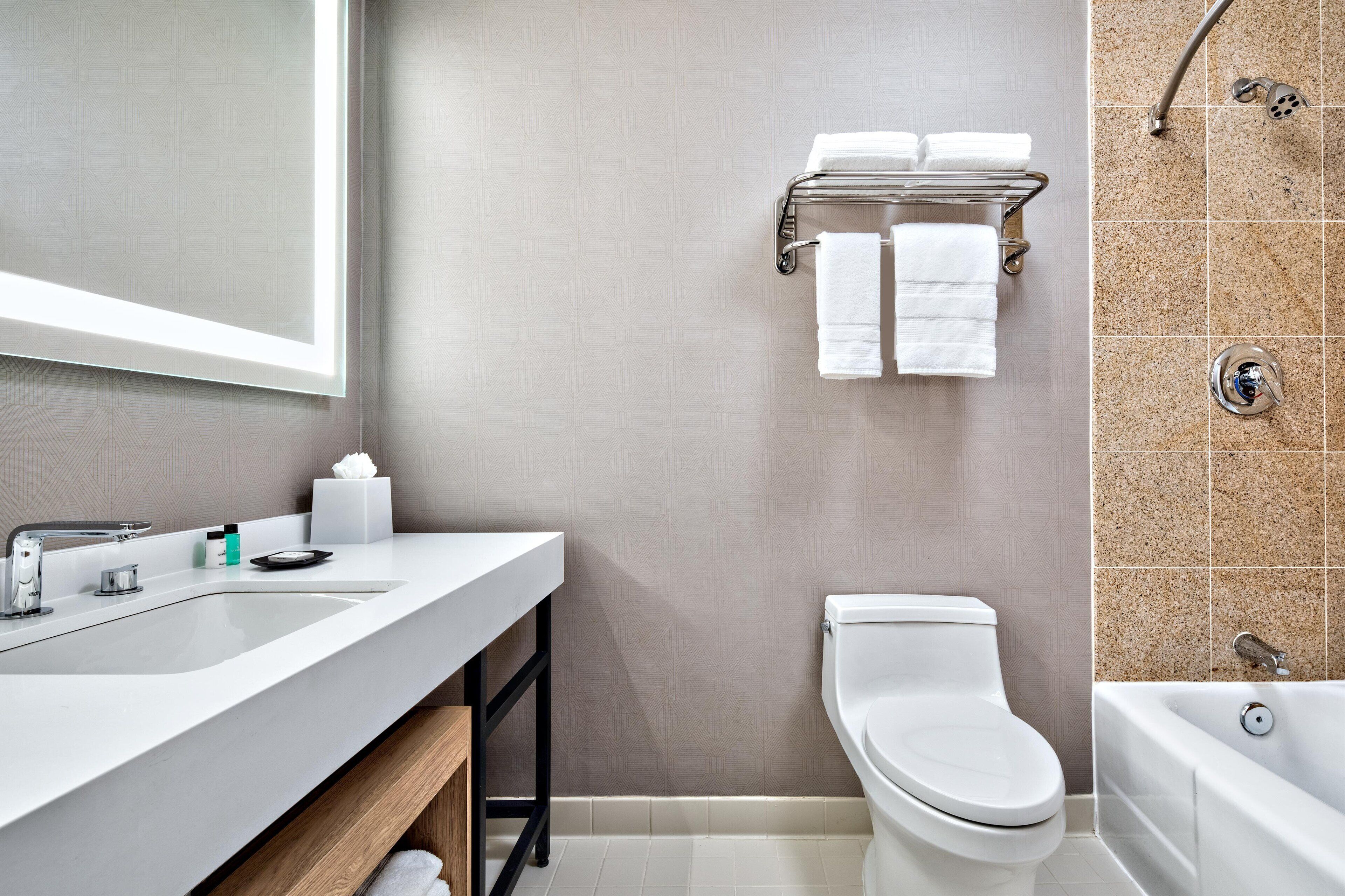 A modern bathroom with a white sink, a toilet, and a bathtub.
