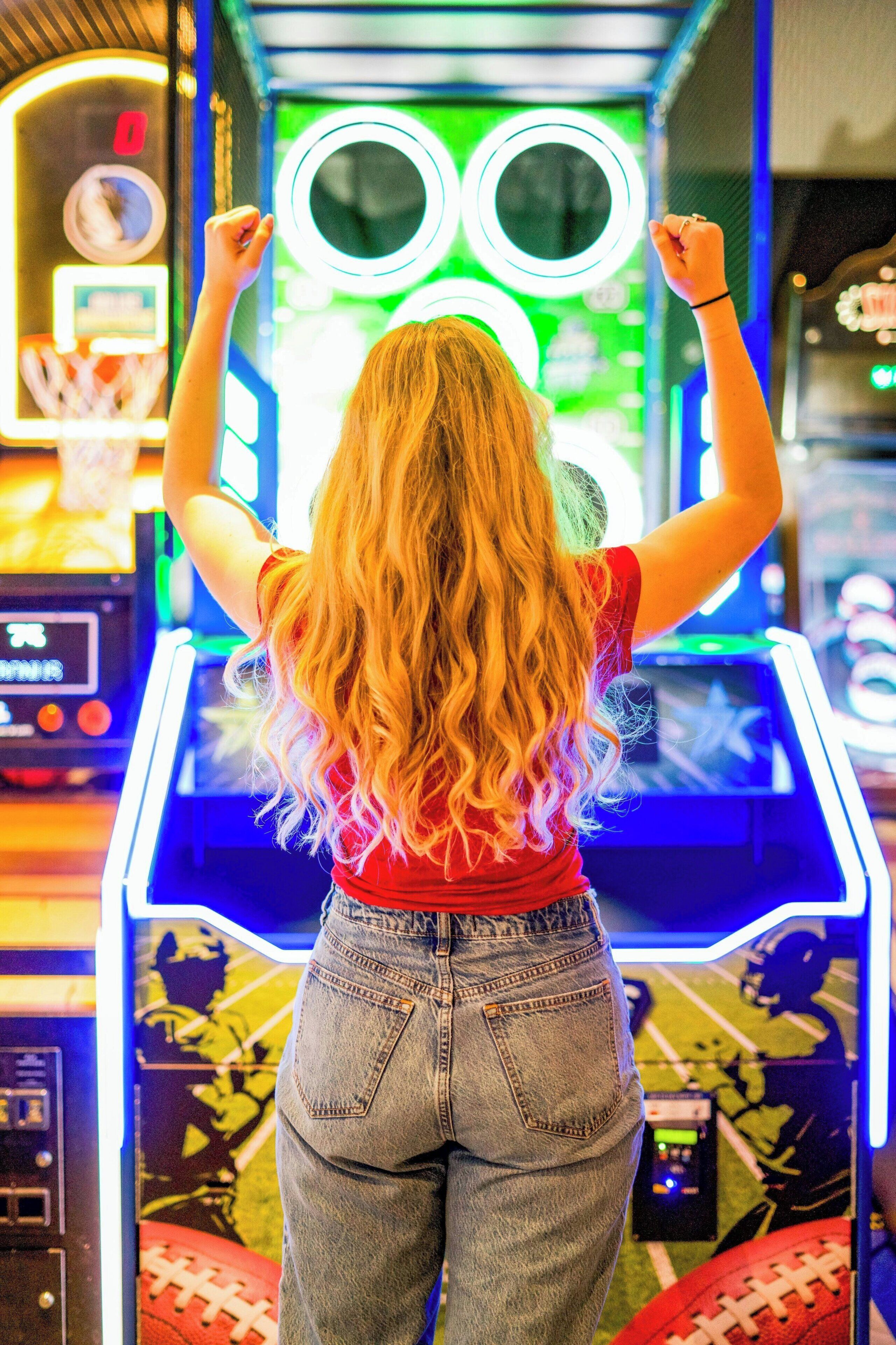 A person standing in front of a gaming machine with a large screen and control panel.