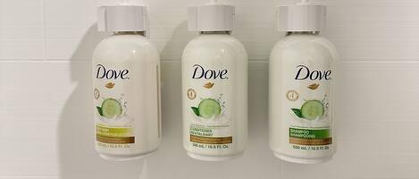 Three Dove shampoo bottles mounted on a white tiled wall.
