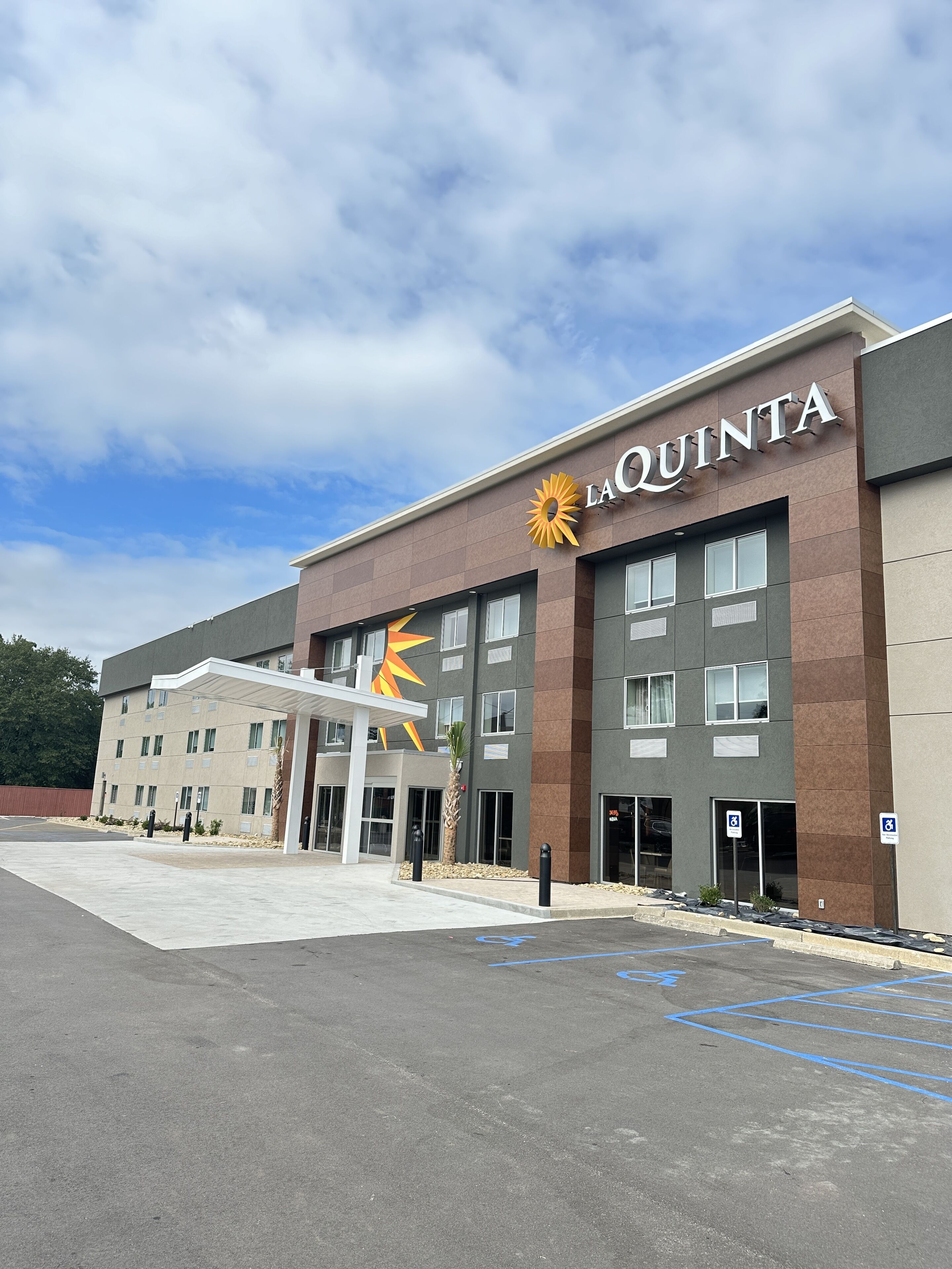 A hotel with a modern facade, a prominent 'LaQuinta' sign, and a covered entrance area.