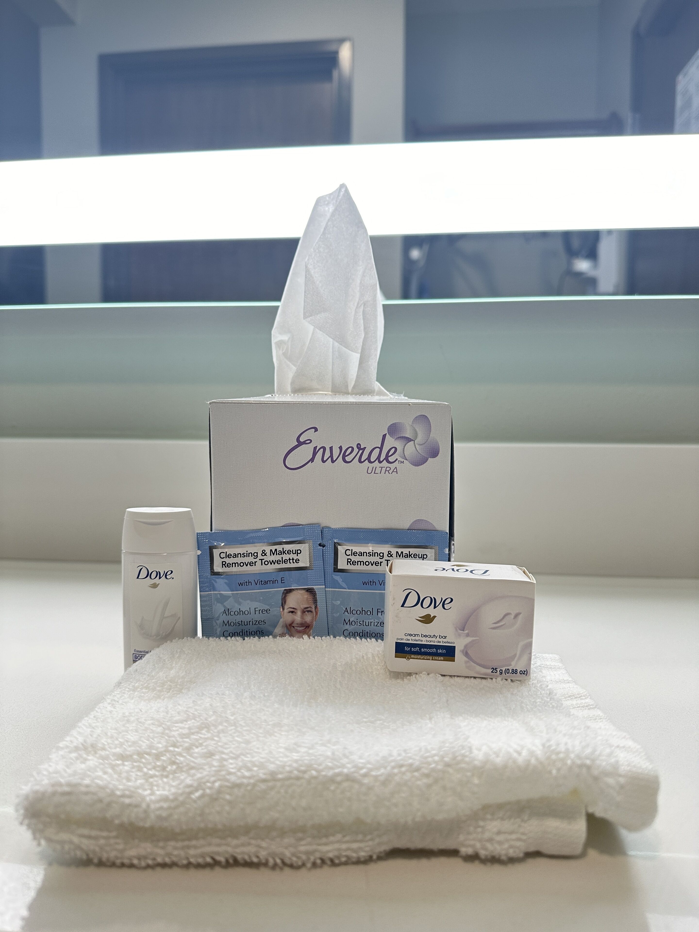 A bathroom with a white towel, Dove cleansing and makeup remover tissues, and a Dove cream bar.
